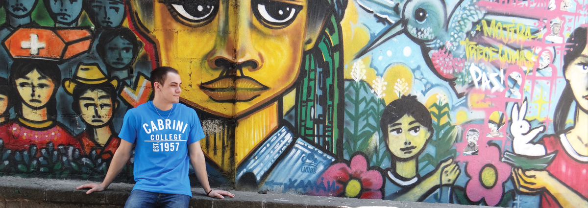 A Cabrini student in front of a mural during a study abroad trip