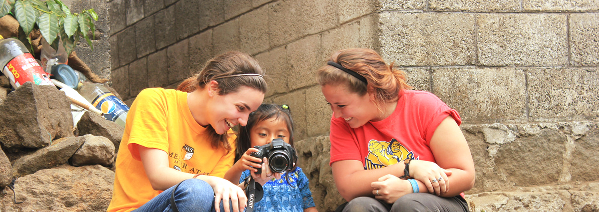 Cabrini students showing their camera to a local child during a study abroad trip