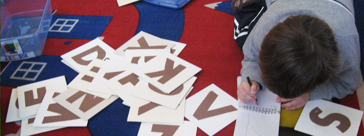 A student at the Children's School practicing writing letters