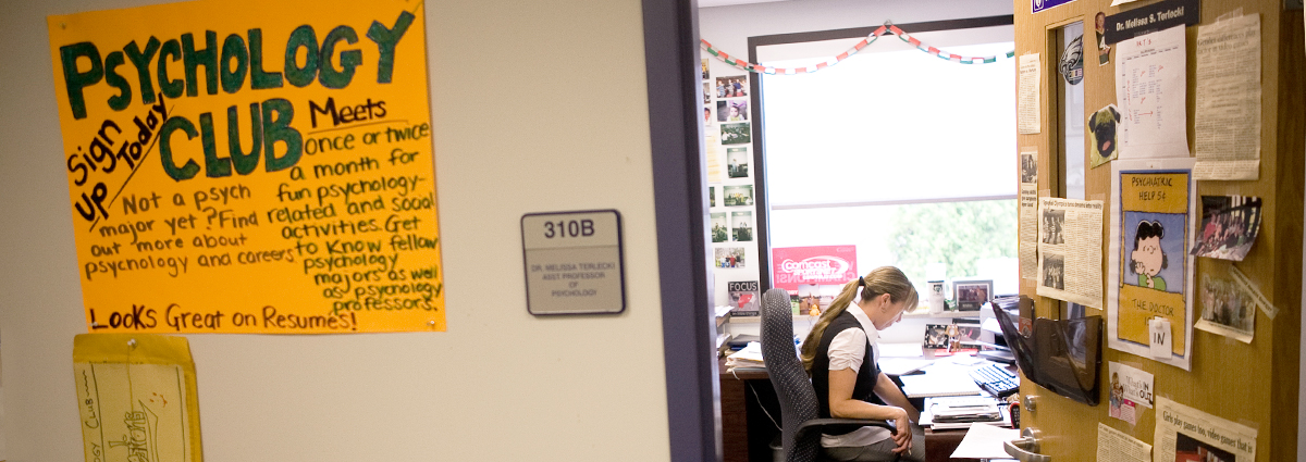 Professor Missy Terlecki in her office with a Psychology Club sign