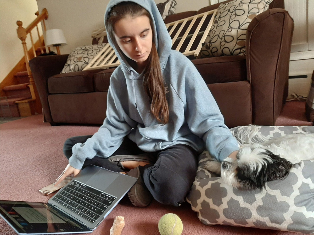 Sarah Lattanze completing homework while petting her dog, Beni