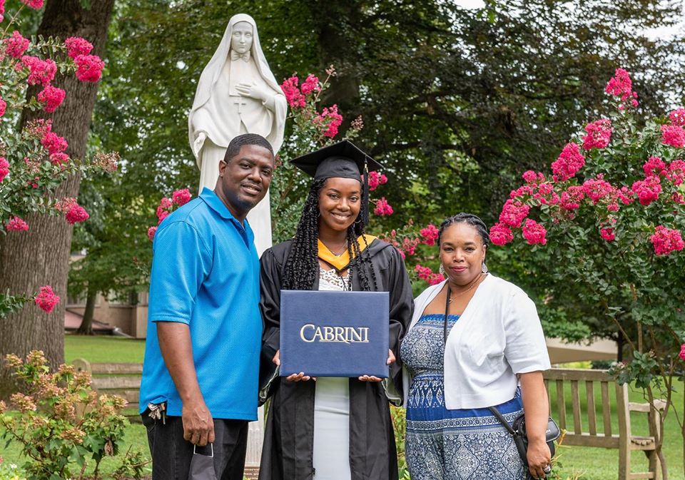A family poses by the Mother Cabrini statue after Commencement.